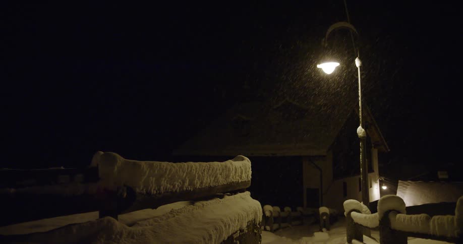A view of snow falling out in front of a street light