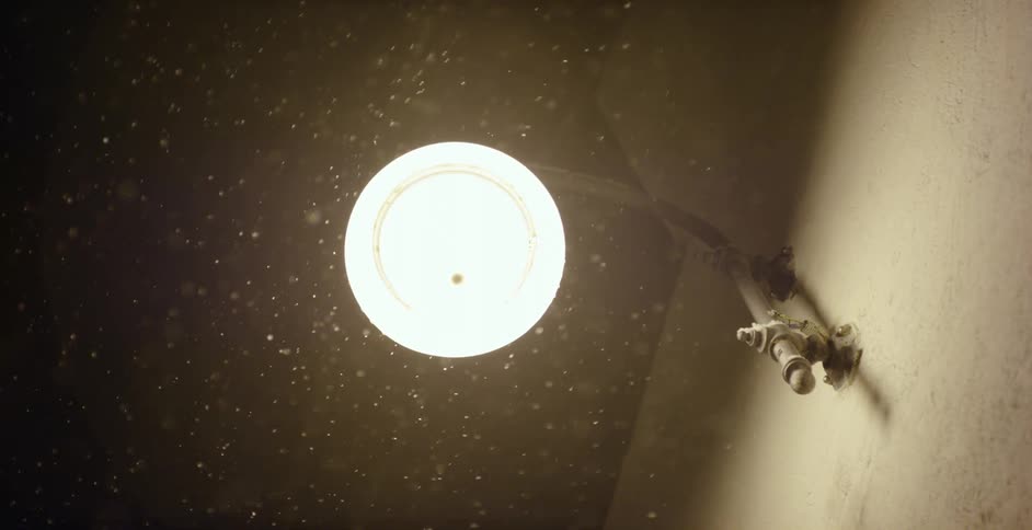 A light fixture on the outside of a building on a snowy night