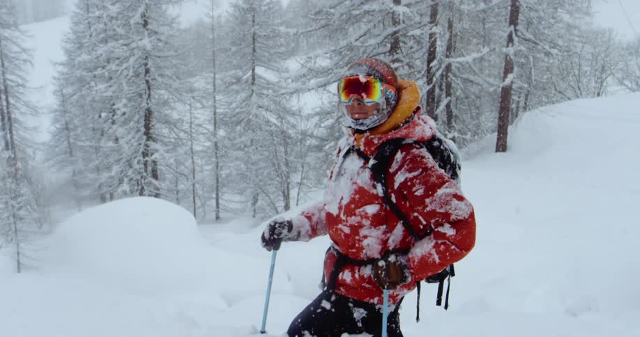 A hiker in a red coat in snowy mountains during a winter storm