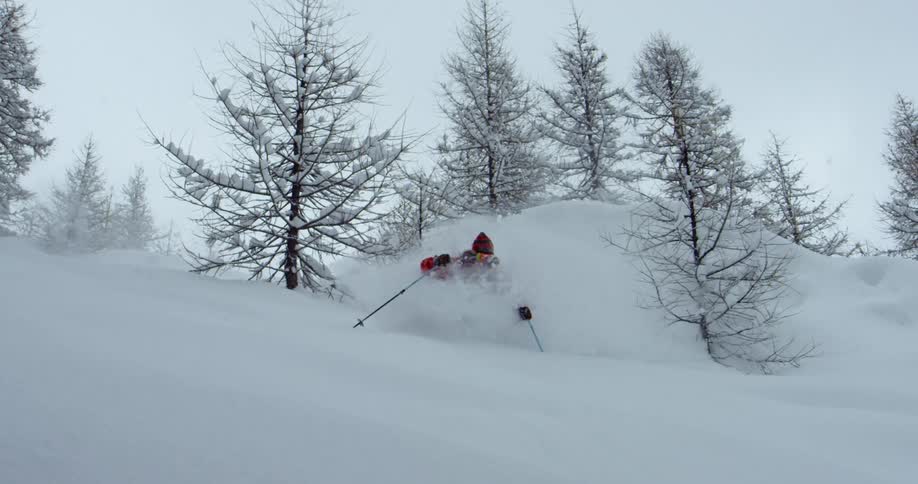 A skier going over a jump in snowy mountains on a winter day