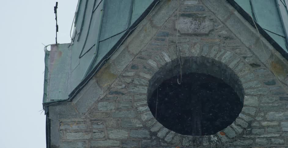 Snow falling in front of a brick building in the winter