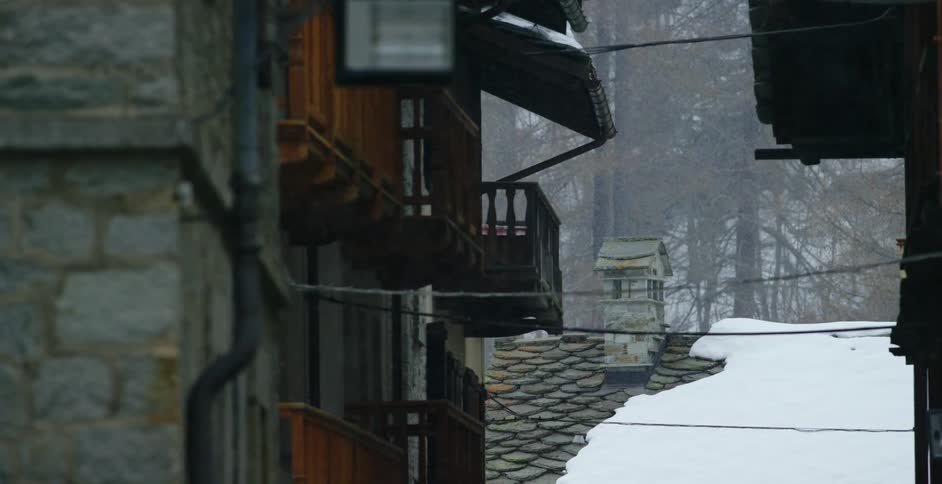 Light snow falls over an apartment building in a rural area