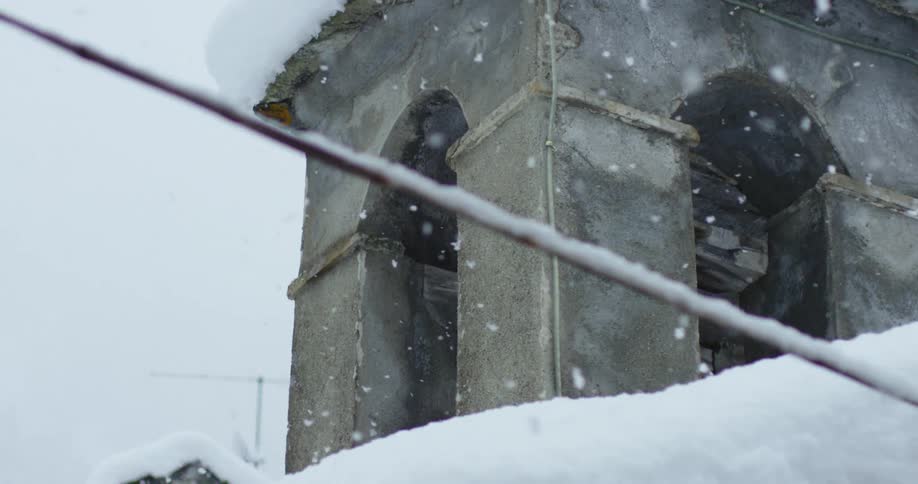 Snow falling around a concrete building on a winter day