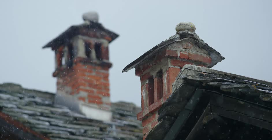 Snow falling around brick chimneys in winter