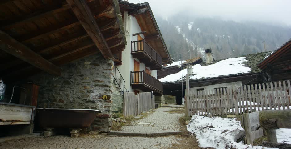 Light snow falls over an apartment building in the countryside