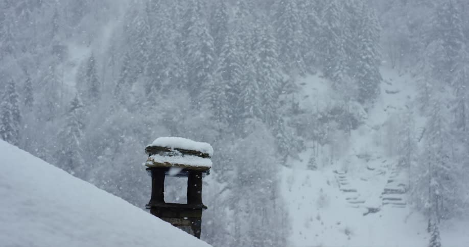 Thick snow falls from the sky onto a mountain slope holding a stone well