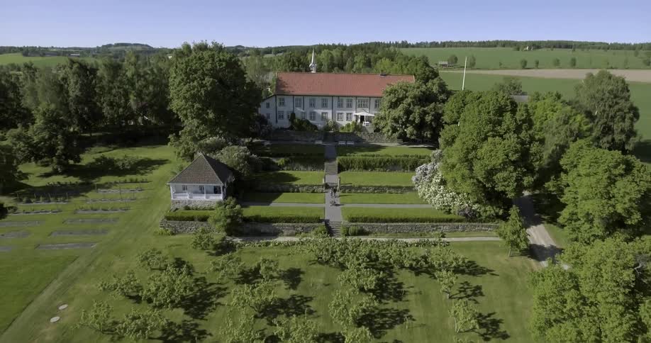 Aerial view of a large home with people walking down the steps in front
