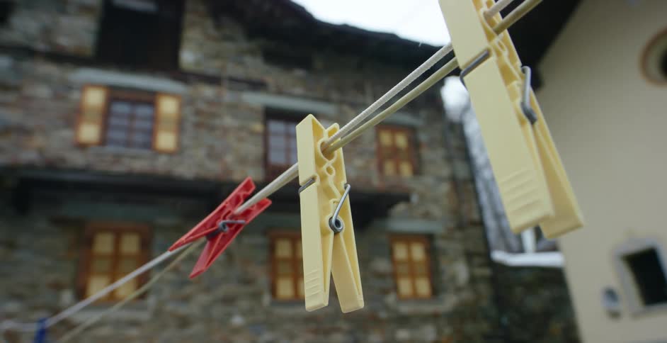 Snow falls behind an apartment building where a clothesline hangs in the yard