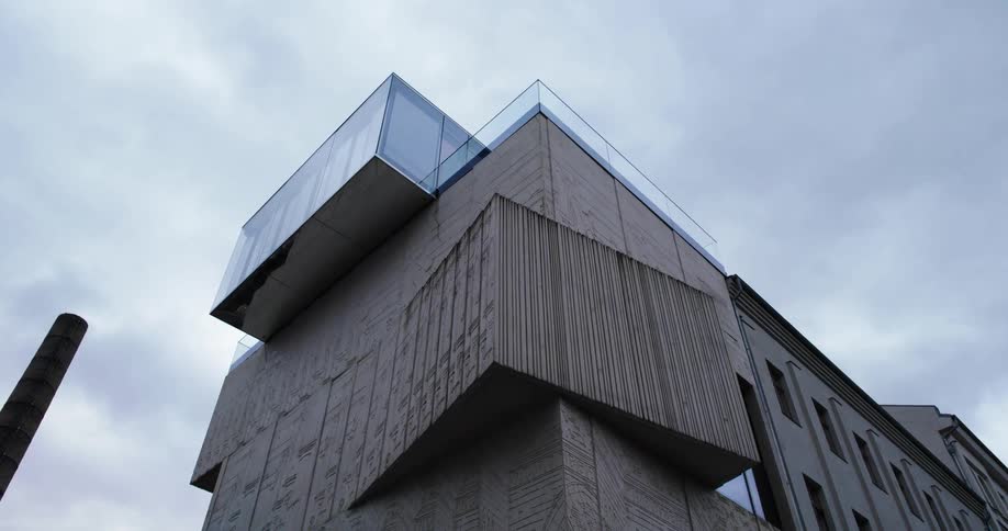 A building is displayed in a city on a cloudy day