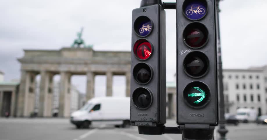 A traffic sign lights up on a busy street with cars driving and people riding bikes