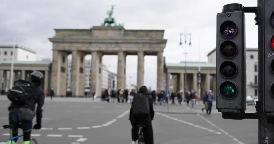 People ride bicycles across an intersection filled with pedestrians in a large city