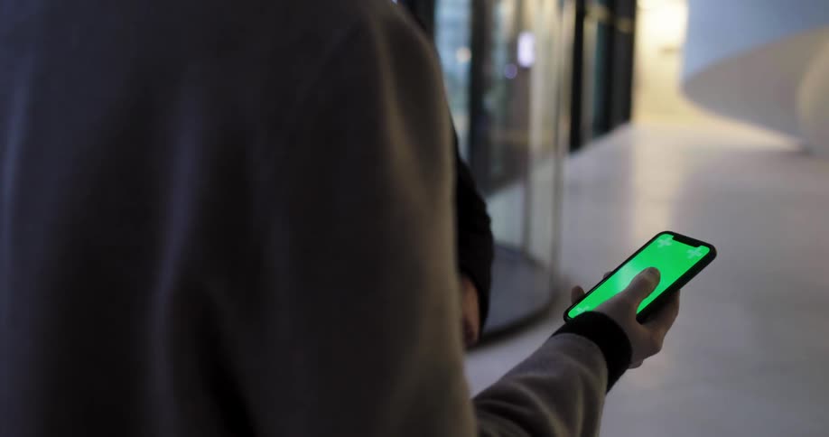 Two people talk outside business store in hall referencing mobile phone