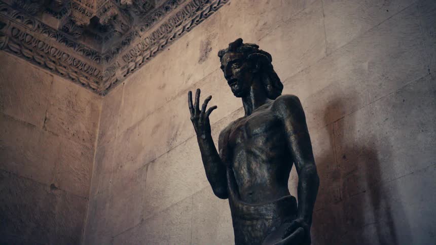 The large statue of a human sits against the wall