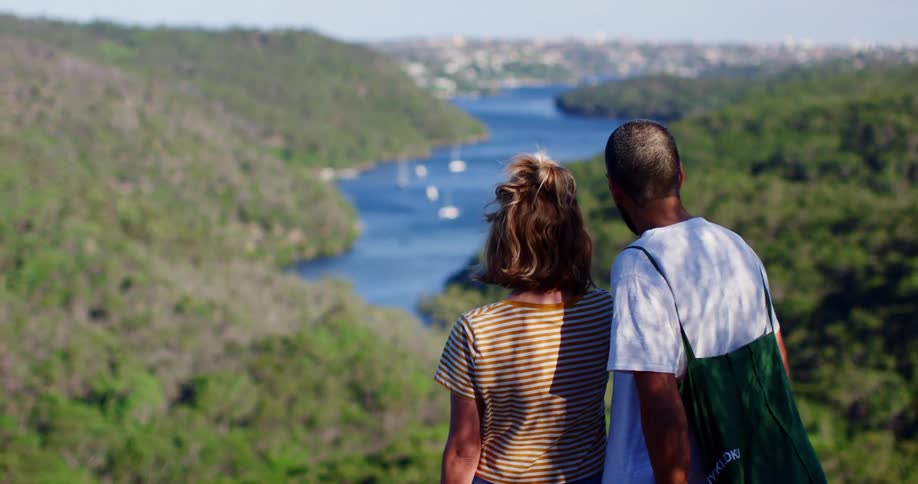 A man and woman stand and looks at sailboats on the water