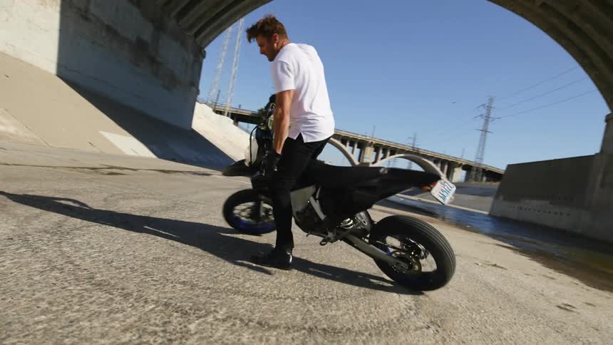 A man doing doughnuts on a motorcycle in a dry river