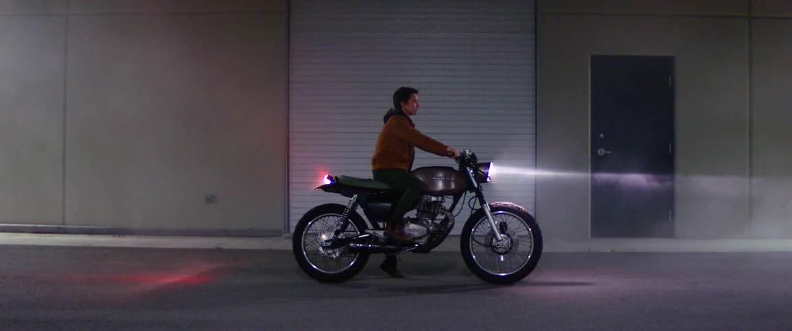 A man is sitting on a motorcycle at night