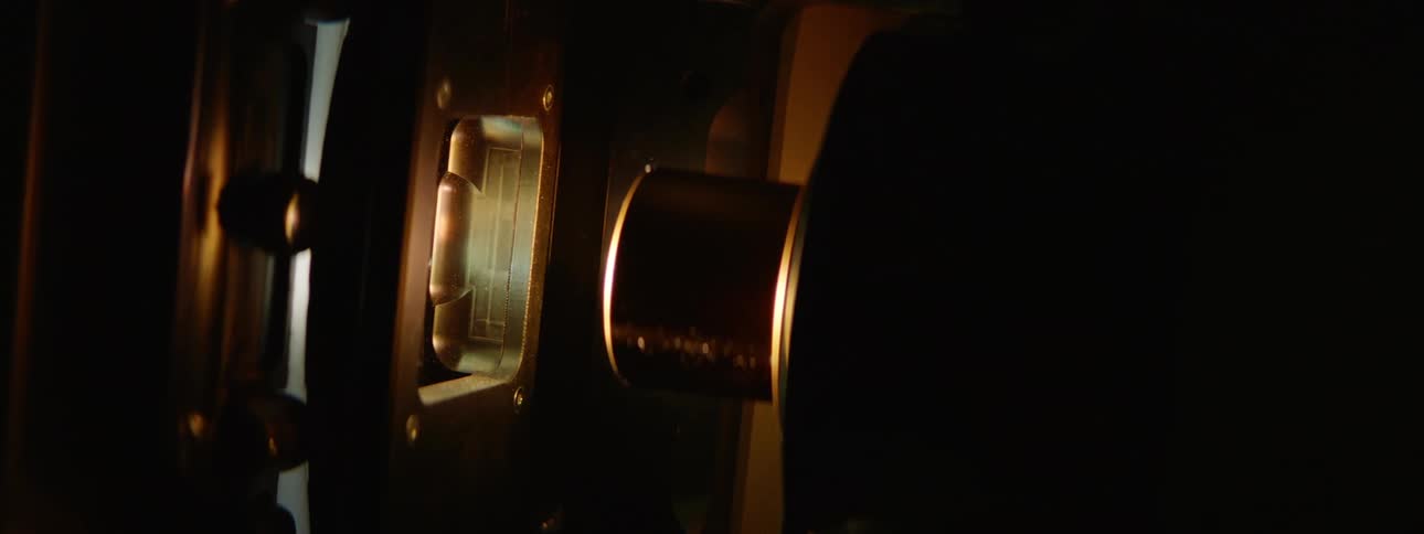 Lights flash on a projector through a small glass screen as a film plays