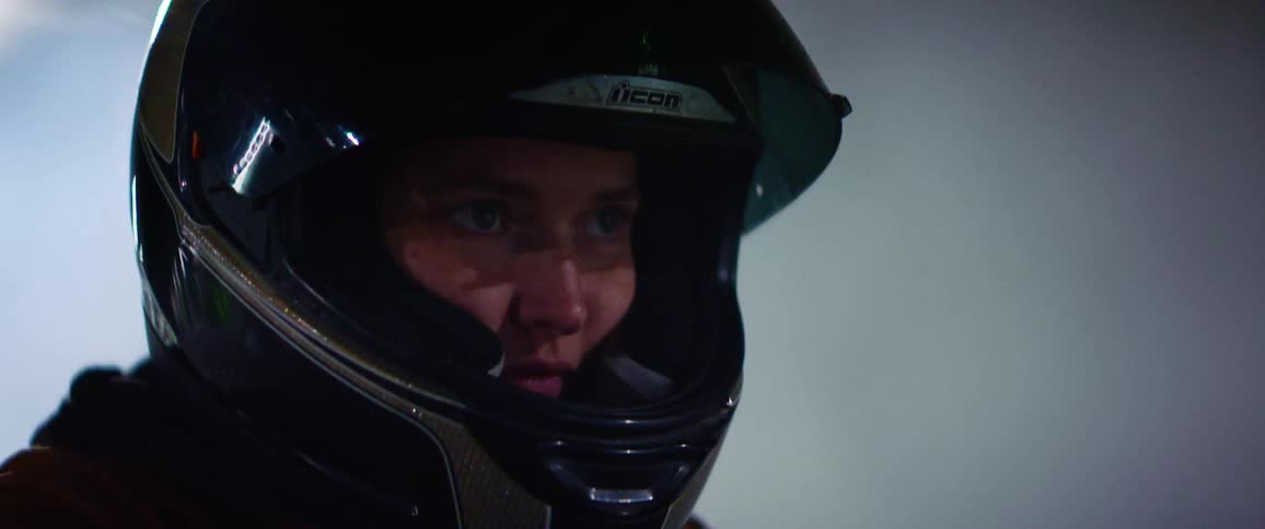 A woman is riding a motorcycle outdoors at night