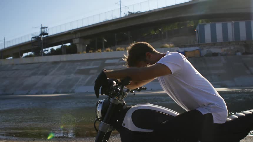 A man is sitting on his motorcycle during the day