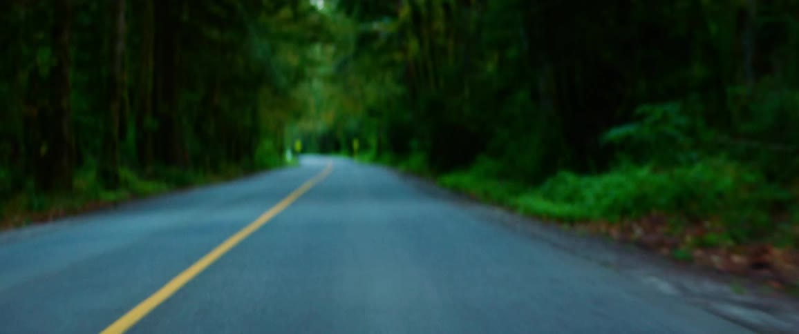 A man is riding a motorcycle down an empty road