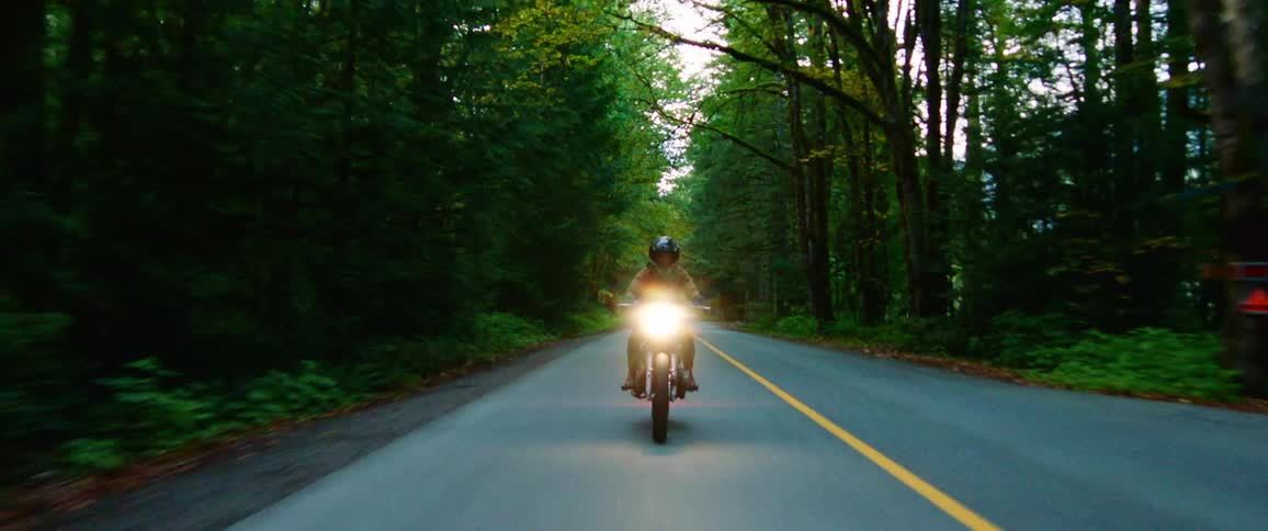 A man is riding a motorcycle down a road