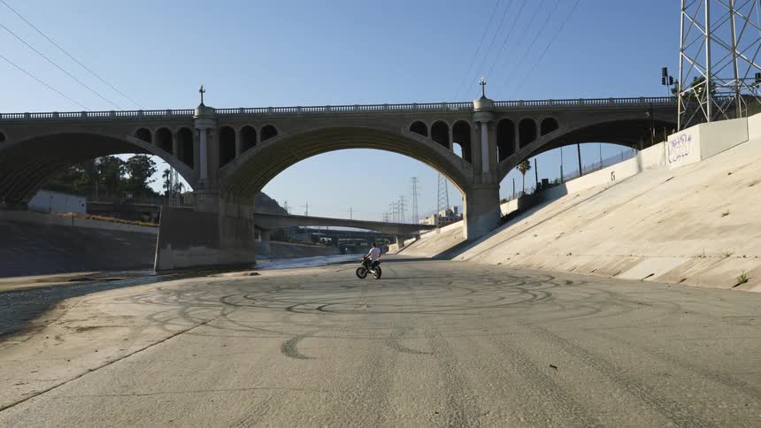 A man is sitting on his motorcycle in the empty canal