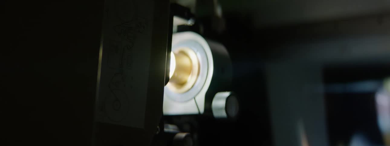 A movie projector plays a film in a dark theater