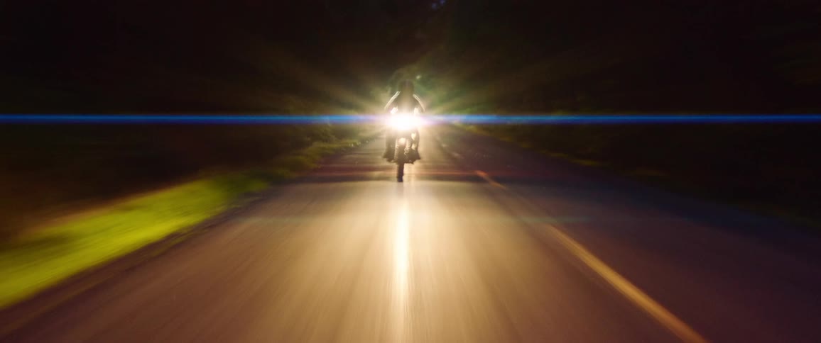 A person driving a motorcycle down a street at night