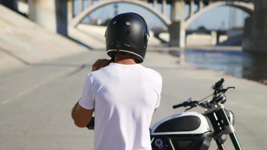 A guy is walking towards his motorcycle during the day