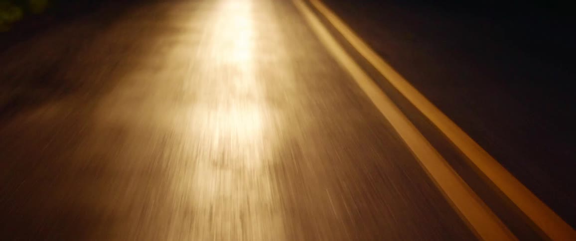 Headlights illuminating a paved road at night