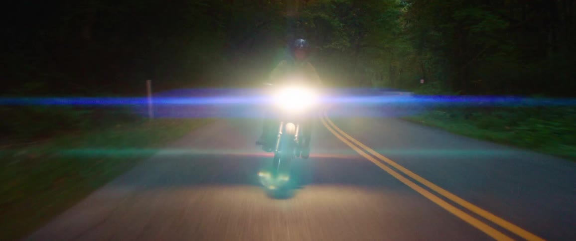 A man is riding a motorcycle down an empty road