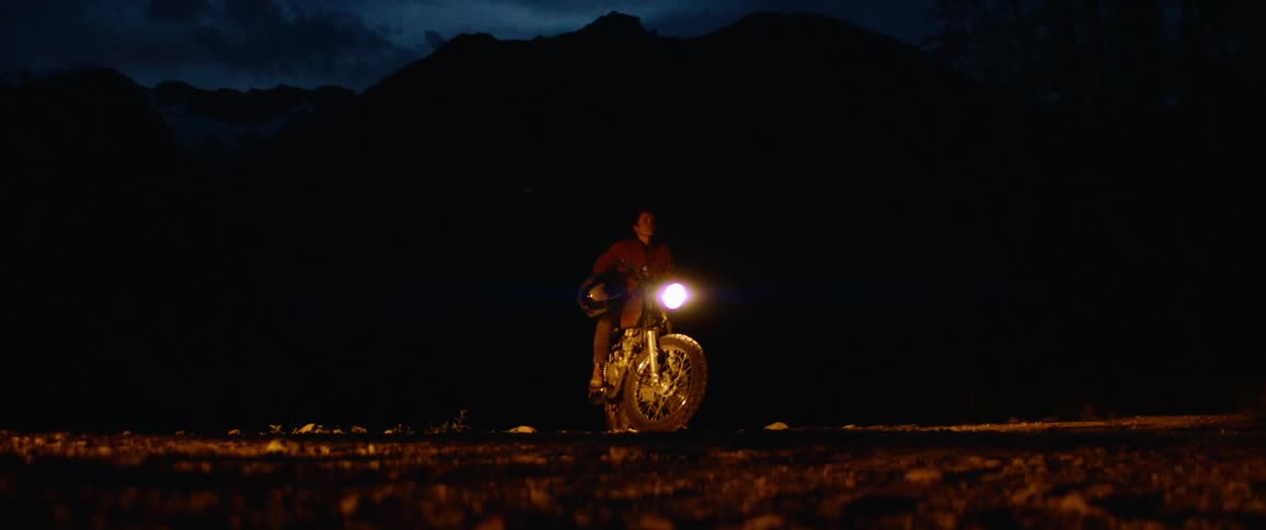 A man is standing by his motorcycle at night