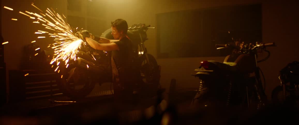 A woman does some welding on her motorcycle in the garage