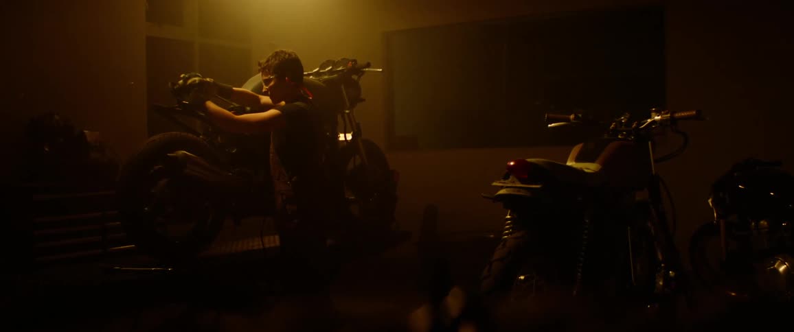 A man using a machine to weld on a motorcycle in a shop