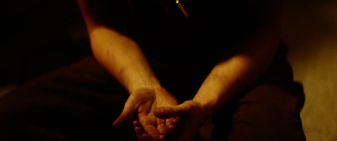 A man applies hand sanitizer to his palm and rubs his hands together in a dim room
