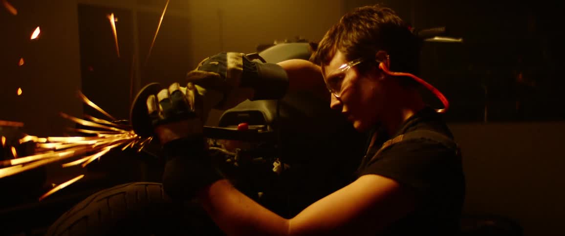 Sparks fly as a woman works on her motorcycle