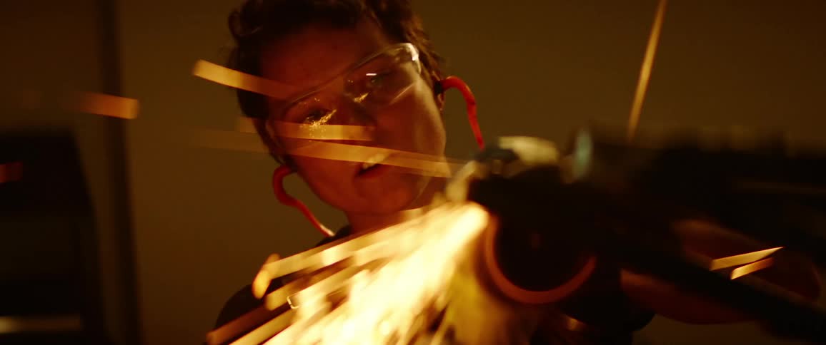 Woman grinds metal railing with power tool creating a shower of sparks