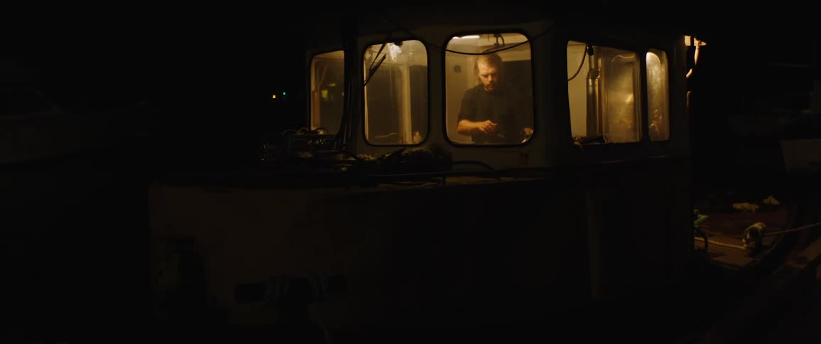 A man wipes down tools with a rag in a small room with several windows