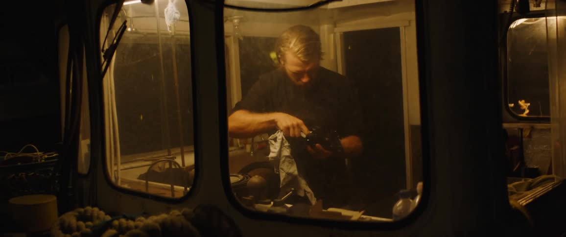 A man cleaning a snorkel with a cloth in the cabin of a boat
