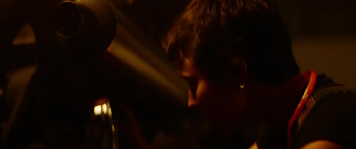 A woman in a dimly lit garage changes the socket on a socket wrench before using the tool on the back of a motorcycle