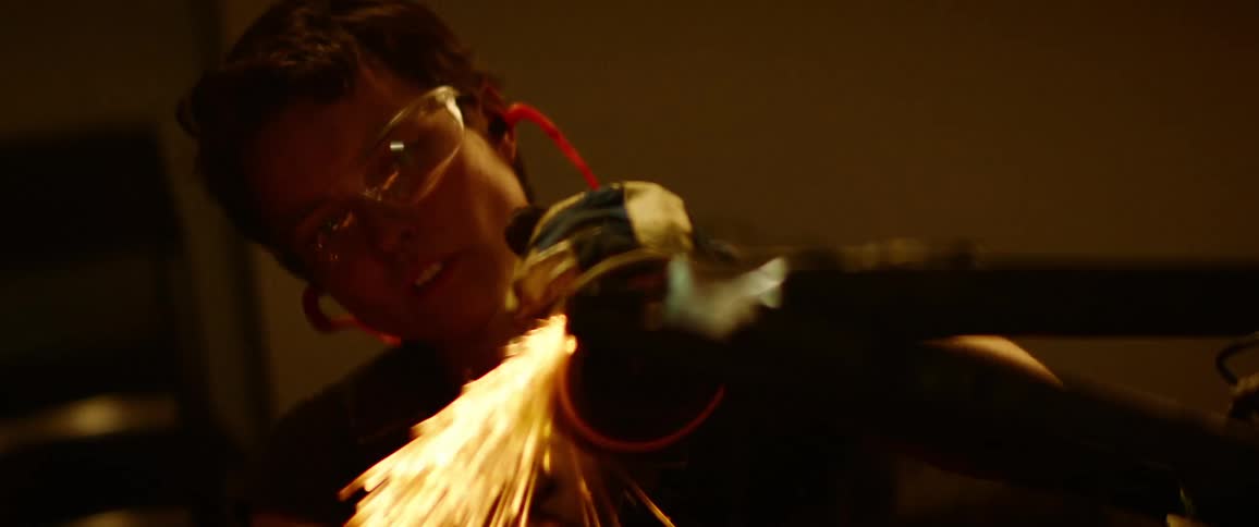 A welder wears safety goggles to protect from sparks flying as metal is grinded with a tool