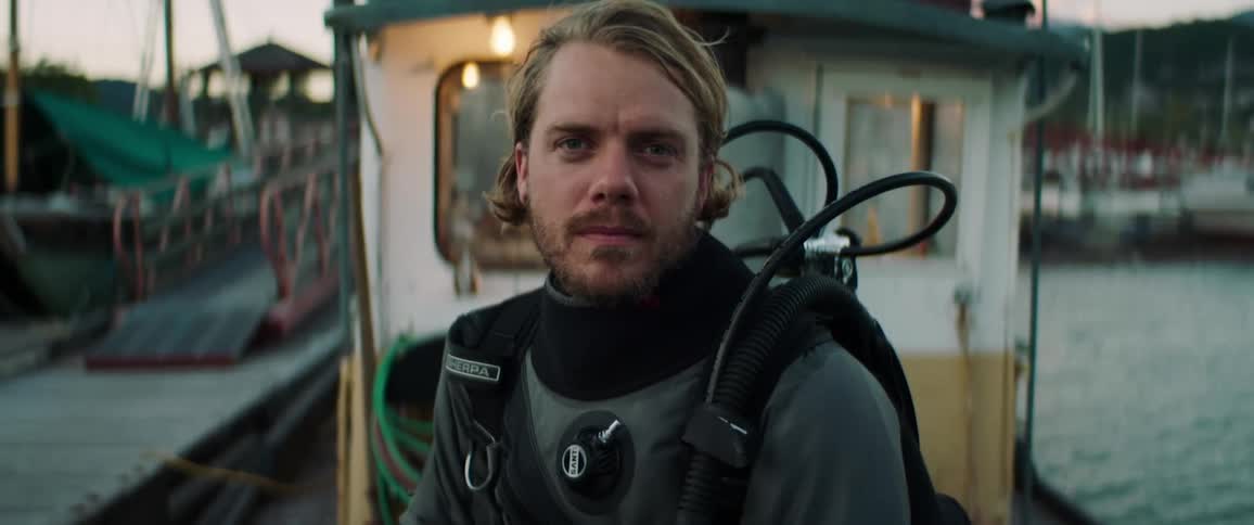 Man in scuba gear sits on boat in marina
