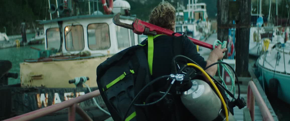 A man walking down a dock carrying scuba equipment