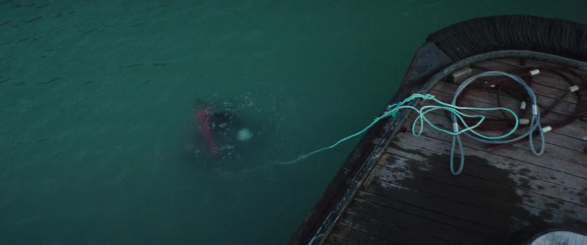 A diver takes a deep breath before going underwater while tied to a nearby boat