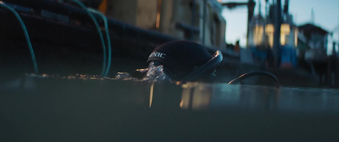 A man diving off the edge of a boat with a flashlight