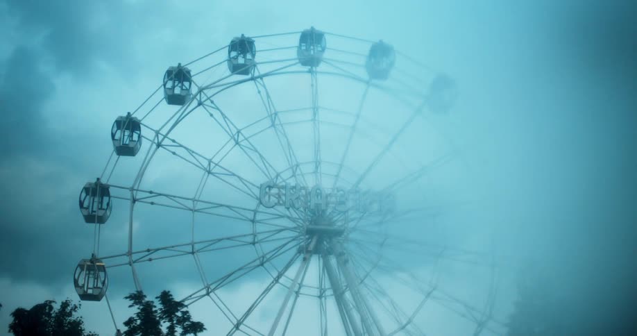 A still ferris wheel under a cloudy evening sky