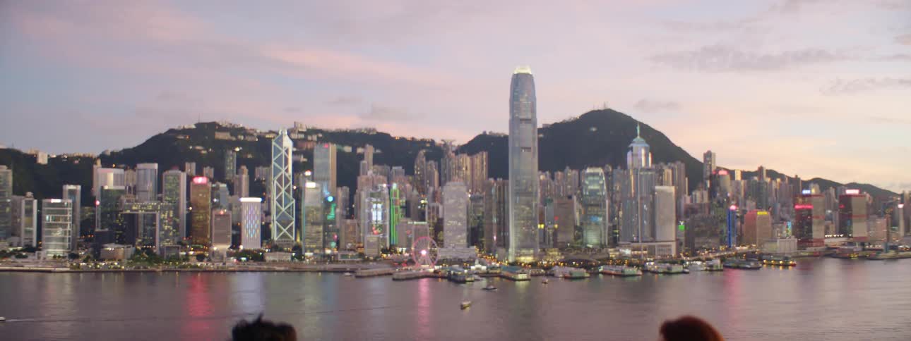 People eating and drinking at a restaurant overlooking a city at dusk