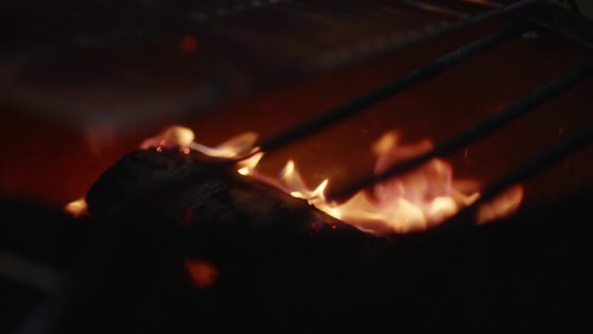 A small fire burns a small piece of wood in the darkness