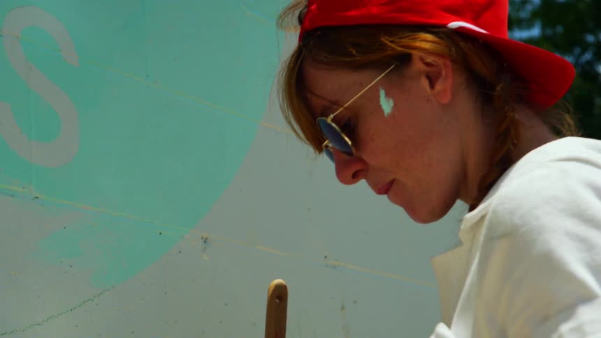 A woman is painting a wall outdoors in spring