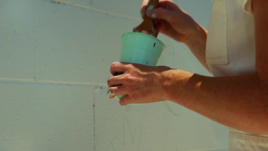A woman is painting a wall outdoors